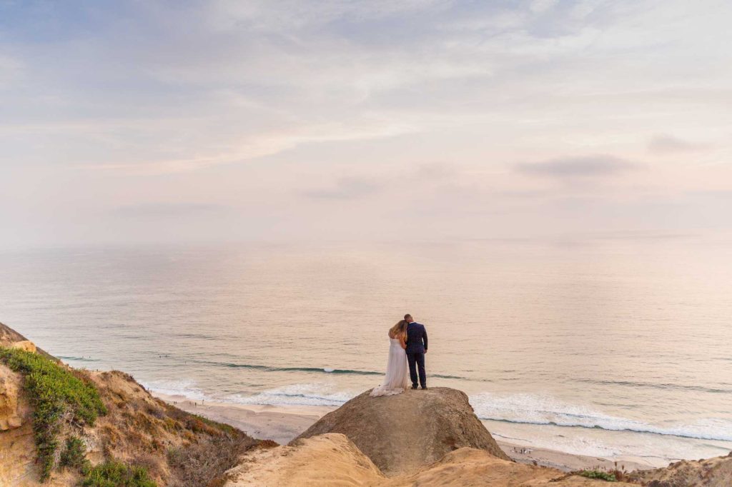 eloping couple staring out at the beach