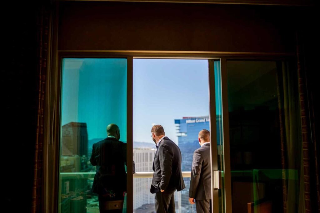 groom and company stare out at the strip on their balcony before they head out for a desert elopement